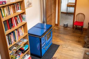 een blauwe kachel in een kamer naast een boekenplank bij 3-Bed Lodge with direct access to the Tarka trail in Great Torrington
