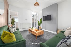 ein Wohnzimmer mit einem grünen Sofa und einem Tisch in der Unterkunft Campbell House by Truestays - NEW 2 Bedroom House in Stoke-on-Trent in Trent Vale