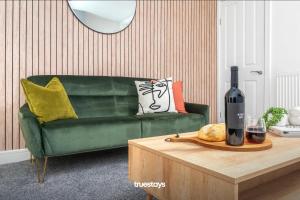 a living room with a green couch and a table with a bottle of wine at Campbell House by Truestays - NEW 2 Bedroom House in Stoke-on-Trent in Trent Vale
