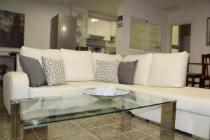 ein Wohnzimmer mit einem weißen Sofa und einem Glastisch in der Unterkunft Apartamento Boutique Cruce de Melenara in Melenara
