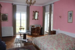 una camera da letto con pareti rosa, un letto e un tavolo di Château de Grandval - Sainte Mere Eglise a Neuville-au-Plain
