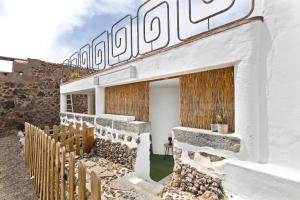 a white building with a fence next to it at KORÉ aljibe in Tías