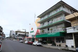 a building with cars parked on the side of a street at Frota Palace Hotel in Macapá