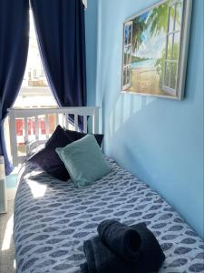 a bedroom with a bed with blue walls and a window at Seaview Apartment with parking in Exmouth