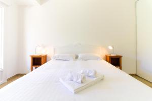 Un dormitorio con una cama blanca con toallas. en Villa entre Rose et Pins à Bormes-les-mimosas 4 étoiles - ROSES&PINS, en Bormes-les-Mimosas