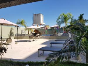 un patio avec des bancs, des tables et des parasols dans l'établissement Apartamento Serra Park, à Rio Quente