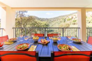 una mesa azul con comida y copas de vino en el balcón en Villa entre Rose et Pins à Bormes-les-mimosas 4 étoiles - ROSES&PINS, en Bormes-les-Mimosas