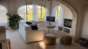 ein Wohnzimmer mit einem weißen Sofa und einem TV in der Unterkunft Casa El Sueño in Jávea