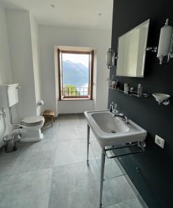 baño con lavabo y aseo y ventana en Historic villa with magnificent lake views, en Valsolda