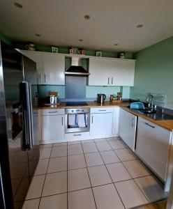 a kitchen with white cabinets and a stove top oven at Beautiful Marina Apartment with private garden, flexible bedrooms with zip & link beds in Gosport