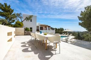 un patio con mesa, sillas y piscina en Villa Casiopea, en Ibiza