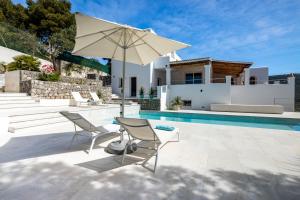 un patio con 2 sillas y una sombrilla junto a la piscina en Villa Casiopea, en Ibiza