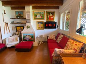 un soggiorno con divano rosso e quadri alle pareti di Casa Vista lago - 24h Check in - Free WiFi - Netflix a Monte Isola