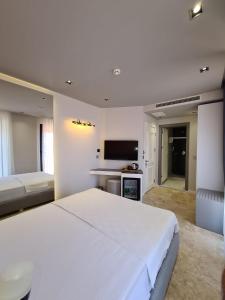 um quarto branco com uma cama grande e uma televisão em Delice Mavi em Ildır