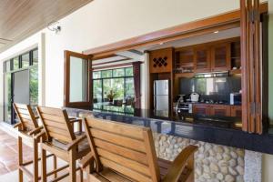 eine Küche mit 4 Stühlen und einer Theke mit einer Bar in der Unterkunft Residence Lake Rawai in Phuket