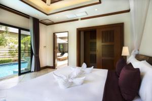 a bedroom with a white bed and a swimming pool at Residence Lake Rawai in Phuket Town
