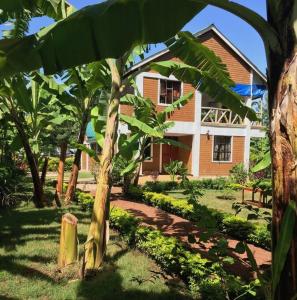 a house with a palm tree in front of it at Hondo Hondo House in Mto wa Mbu