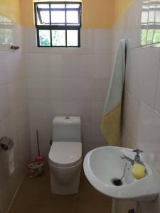 a white bathroom with a toilet and a sink at Hondo Hondo House in Mto wa Mbu