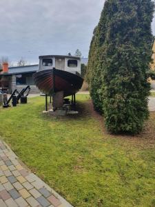 un barco sentado en el césped junto a un arbusto en 100SaulesVikingi, en Grobiņa