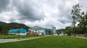 un edificio con un césped verde delante de él en The Sanihara en Vythiri