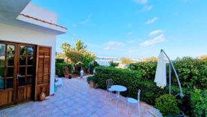 un patio con ombrellone, tavolo e sedie di Alba Chiara B&B a San Vito lo Capo Altre 28 foto