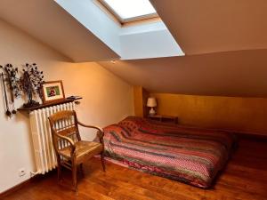 ein Schlafzimmer mit einem Bett, einem Stuhl und einem Dachfenster in der Unterkunft Maison de charme à Montreuil, à 10mn de Paris in Montreuil