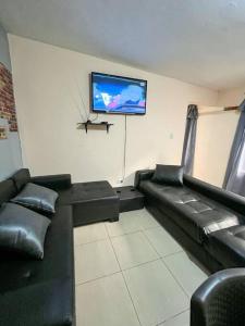 a waiting room with black leather furniture and a flat screen tv at Departamento en centro de Quito. H&O in Quito