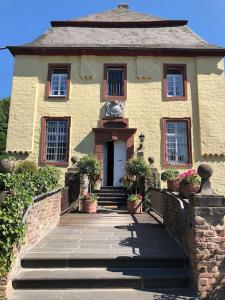 a house with a staircase leading to the front door at Charmante Ferienwohnungen auf Reitstall Wasserburg Anstel - ein Ort zum Wohlfühlen und Entspannen in Rommerskirchen
