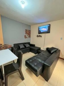 sala de estar con muebles de cuero negro y TV de pantalla plana en Departamento en centro de Quito. H&O, en Quito