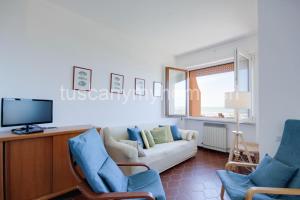 un salon avec un canapé et une télévision dans l'établissement Vela, terrazza sul mare, 2 camere, clima e posto auto a soli 50 m dal mare! by Alfareal, à Castiglione della Pescaia