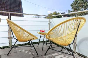 Duas cadeiras e um copo de vinho numa varanda em Lumen Homes - Design-Apt. nahe Audi und Altstadt, 3 Zimmer, NETFLIX em Ingolstadt