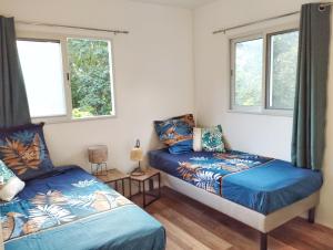 une chambre avec deux lits et deux fenêtres dans l'établissement Kaz Kalina - Gîtes avec piscine partagée, à Bouillante 54 autres photos