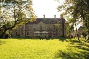 una casa vieja con un gran campo de hierba delante de ella en Château de Grandval, en Neuville-au-Plain