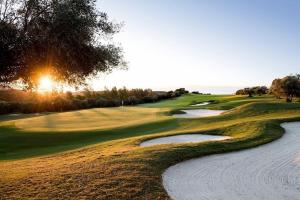 a view of a golf course with the sun setting on at Beachfront Townhouse Estepona in Estepona