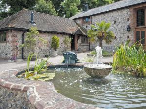 a fountain in the middle of a garden with a building at Owl Cottage - E4092 in Jevington