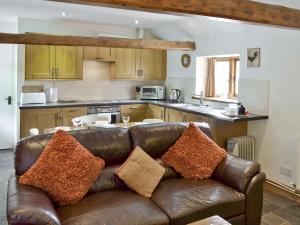 a living room with a leather couch in a kitchen at Owl Cottage - E4092 in Jevington