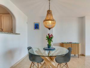 a glass dining room table with two chairs and a chandelier at Beachfront Townhouse Estepona in Estepona