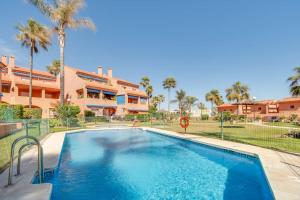 a swimming pool in front of a house with palm trees at Beachfront Townhouse Estepona in Estepona