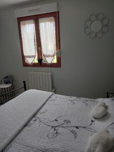 - une chambre avec un grand lit blanc et une fenêtre dans l'établissement La salicorne, à Pendé