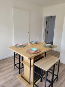a wooden table with plates and wine glasses on it at Les oursins-appartement 3pièces, 4 couchages et parking gratuit in Metz