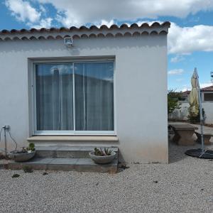 ein weißes Haus mit einem Fenster und zwei Pflanzen in der Unterkunft Paisible P2 pour 4 voyageurs in Saint-Gilles