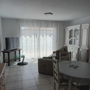ein Wohnzimmer mit einem Sofa, einem TV und einem Tisch in der Unterkunft Paisible P2 pour 4 voyageurs in Saint-Gilles