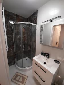 La salle de bains est pourvue d'une douche et d'un lavabo blanc. dans l'établissement Pokoje Gościnne FABIO, à Chojnice