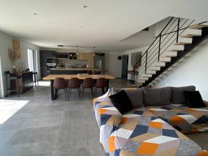 ein Wohnzimmer mit einem Sofa, einem Tisch und einer Treppe in der Unterkunft Maison de 200 m2, récente à Noirmoutier en île in LʼHerbaudière
