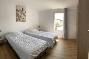 2 Betten in einem weißen Zimmer mit Fenster in der Unterkunft Maison de 200 m2, récente à Noirmoutier en île in LʼHerbaudière
