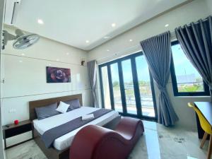 Schlafzimmer mit einem Bett, einem Stuhl und Fenstern in der Unterkunft Motel Hòa Hiệp in Bình Châu