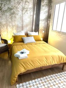 a bedroom with a bed with yellow sheets and trees mural at Cocon cosy hypercentre bordeaux in Bordeaux +12 photos
