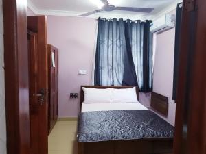 a small bedroom with a bed with a blue curtain at Queen's Hill Lodge in Oblogo