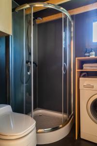 uma casa de banho com um chuveiro, um WC e uma máquina de lavar roupa em Tiny House in the countryside em Årnes