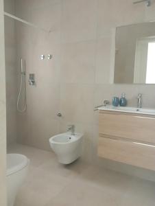 bagno bianco con lavandino e servizi igienici di Sea & Country Rooms a Golfo Aranci